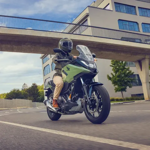 Honda NC750X-Motorrad mit Model auf einer Straße in urbaner Umgebung.